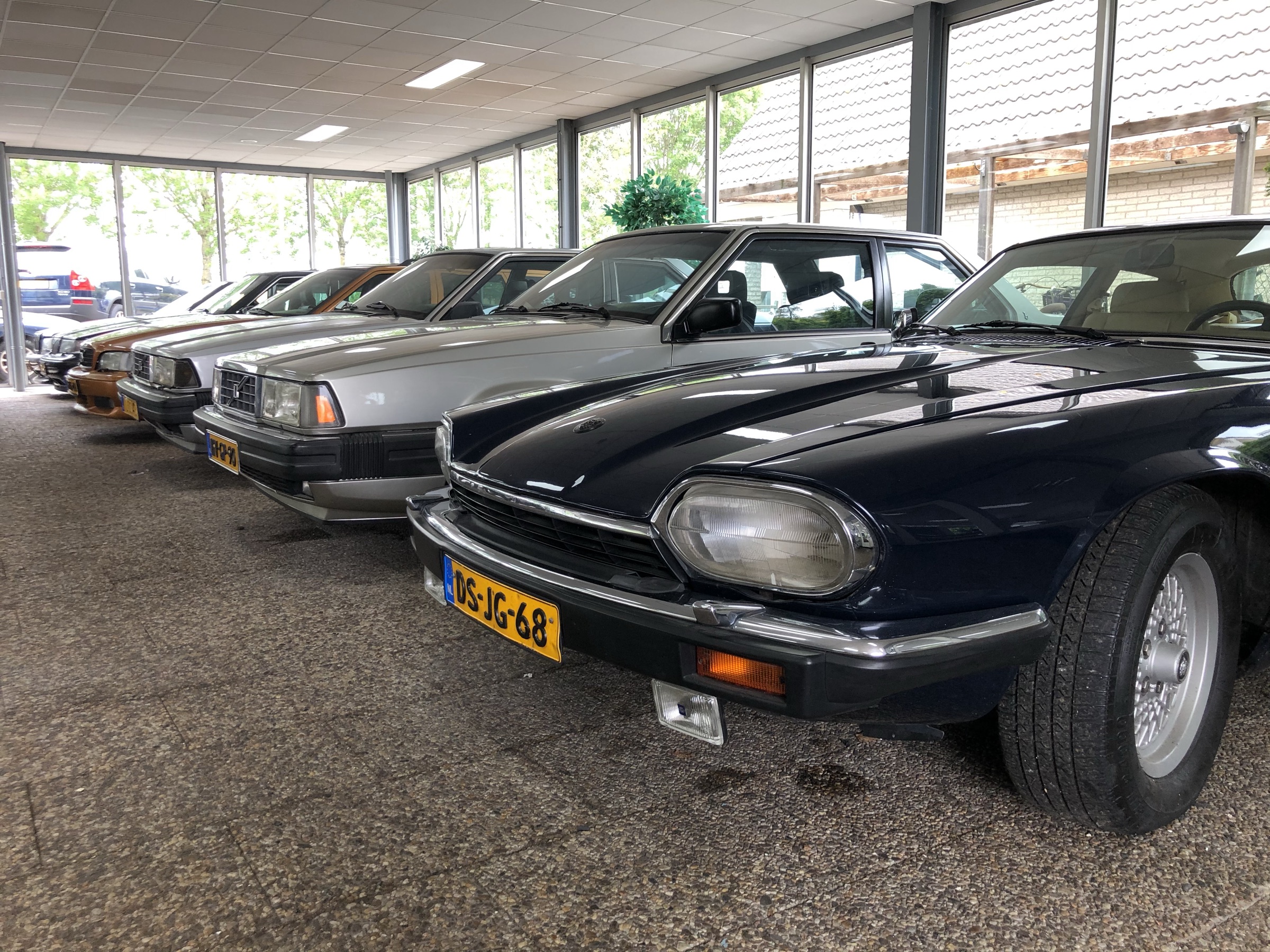 In de showroom: een Jaguar XJS, een Volvo 780 en een rij klassiekers