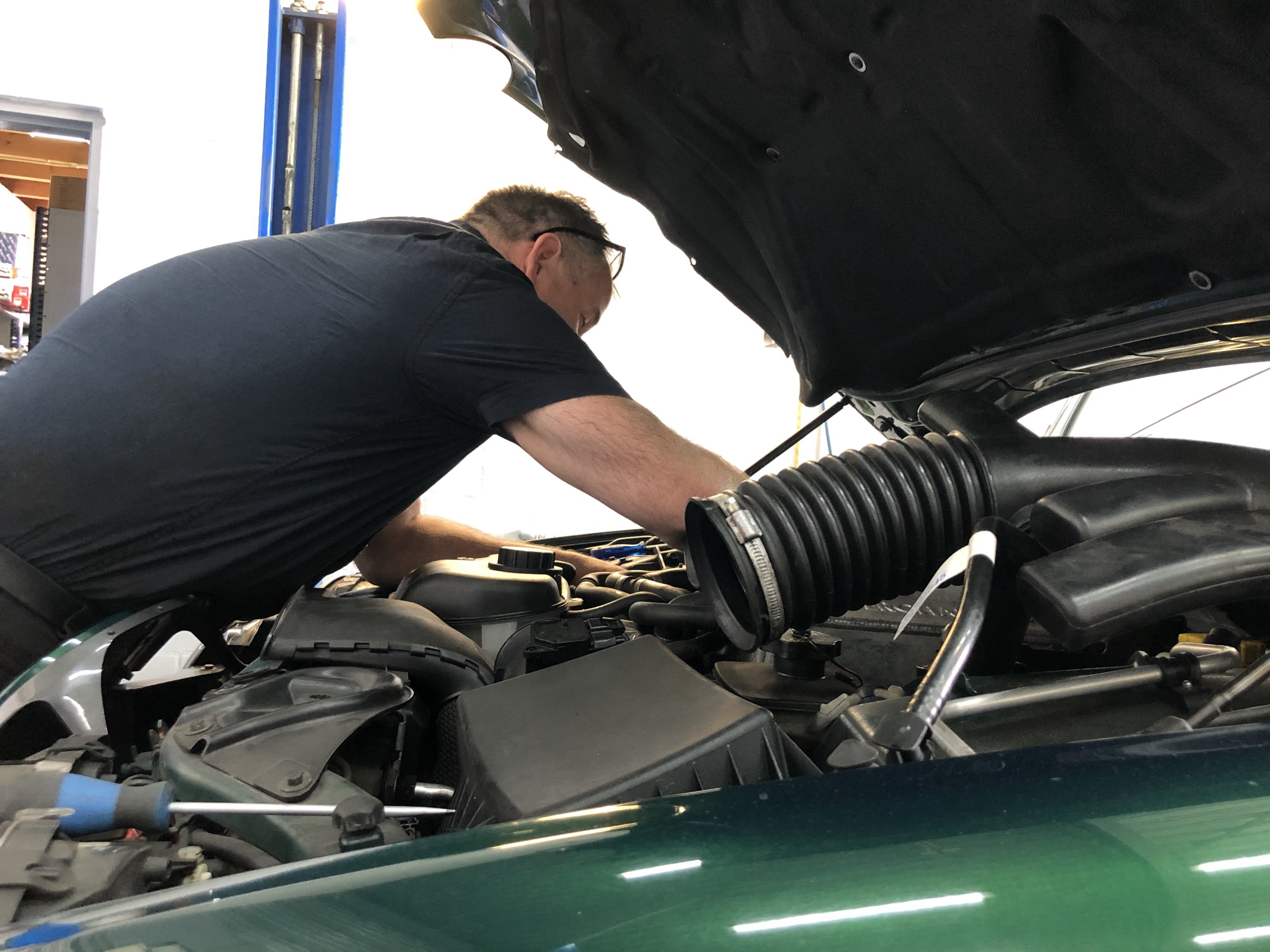 Anno Bunt met het hoofd onder de motorkap van een groene Jaguar